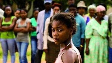 Szenenbild: Ein Mädchen steht vor einer Gruppe von Menschen