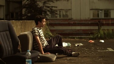 Szenenbild: Ali sitzt in einem Hinterhof auf alten Autositzen