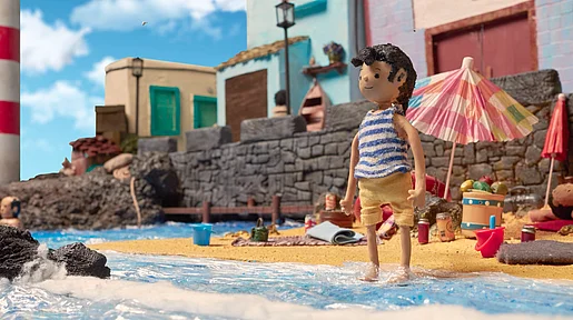 Filmstill Roque, die Meerjungfrau (OT: Cua de sirena), Roque steht am Strand mit den Füßen im Wasser