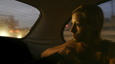 Szenenbild: Layla, auf der Rückband eines Autos sitzend, schaut nach hinten aus dem Fenster, draußen Dämmerlicht