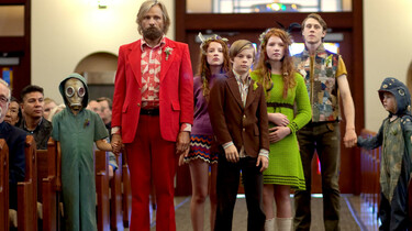 Szenenbild: Ben und seine sechs Kinder in bunter, etwas verrückter Kleidung bei der Trauerfeier in der Kirche