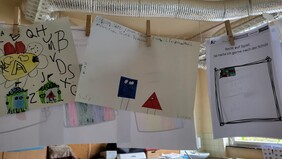 Workshop in einer 1. Klasse: gemalte Bilder zum Kurzfilm EDGY hängen an einer Wäscheleine in einem Klassenzimmer