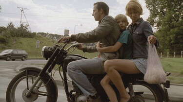 Szenenbild: Junge Frau, Mann und kleiner Junge sitzen auf einem Motorrad